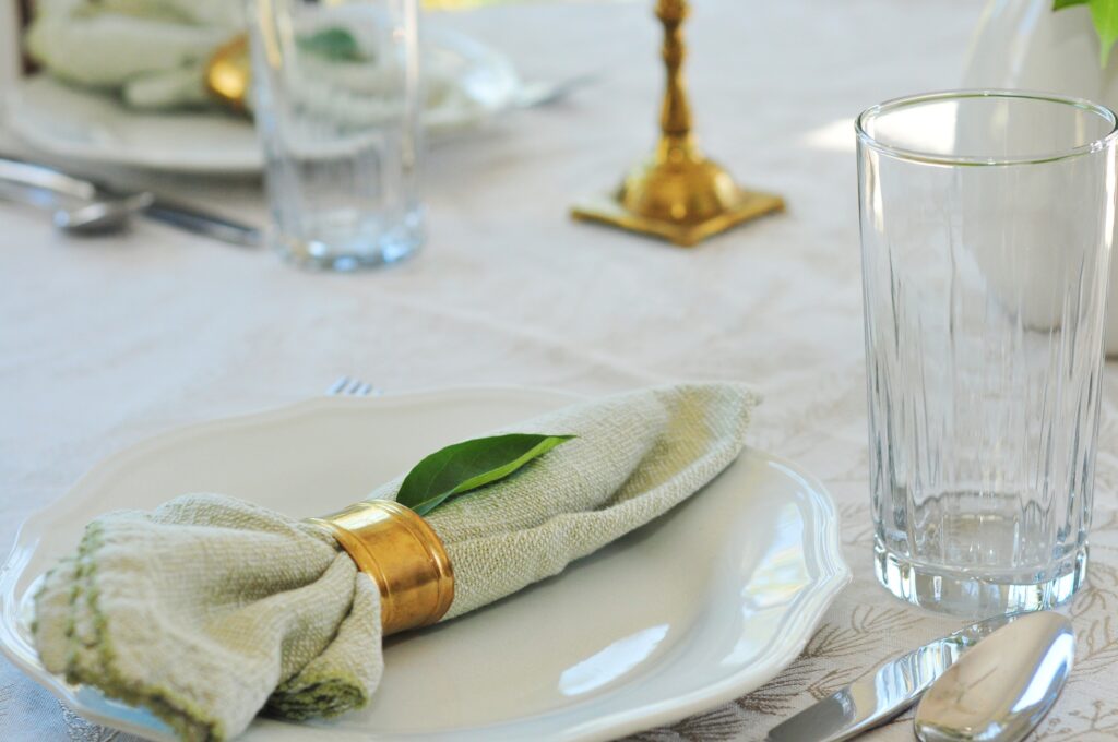 green napkin in gold ring on plate