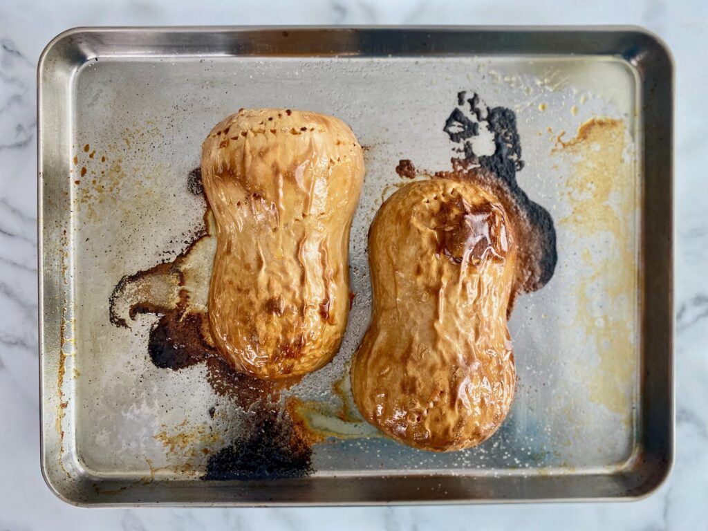 two halves of roasted butternut squash on a cookie sheet