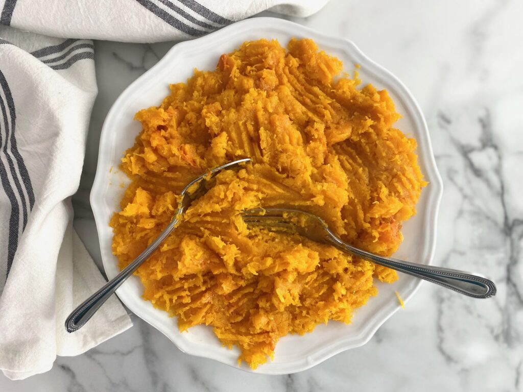 mashed butternut squash with a fork and spoon on a plate