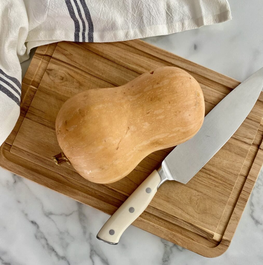 Butternut squash and knife on wooden cutting board