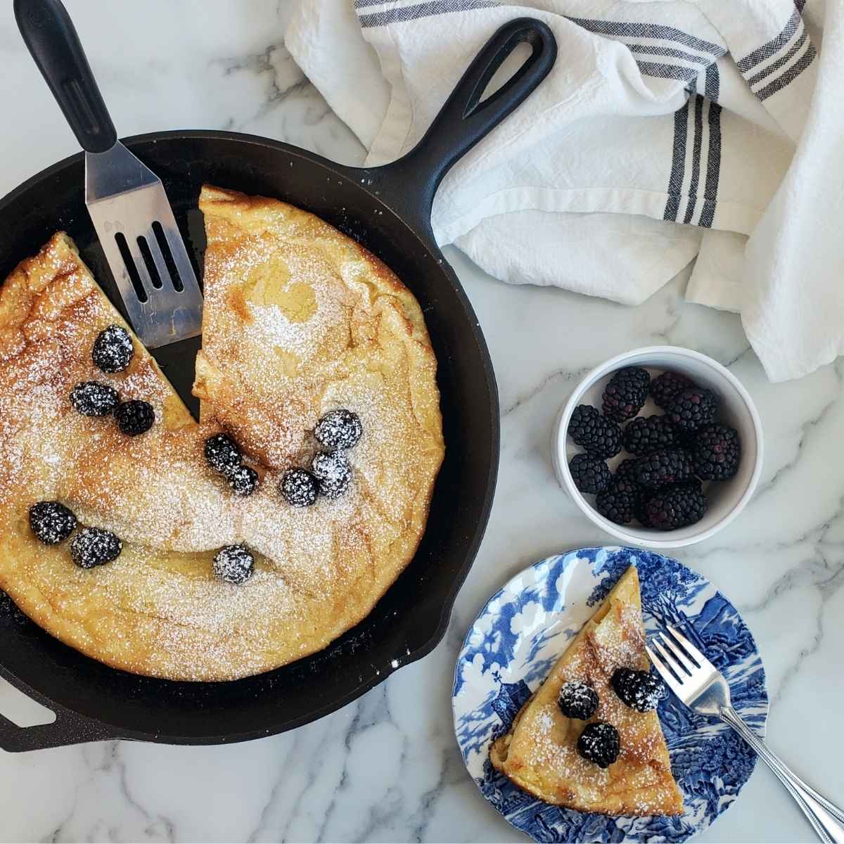 sourdough german pancake in a cast iron skillet with blackberries
