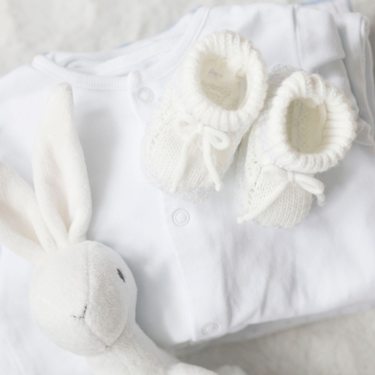 baby booties, onesie, and stuffed bunnie