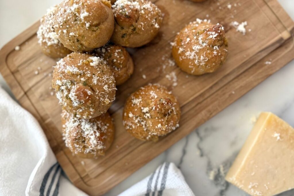 fresh milled sourdough garlic knots with parmesan on a wooden cutting board