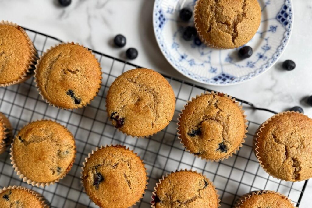 einkorn blueberry muffins on a cooling rack with blueberries