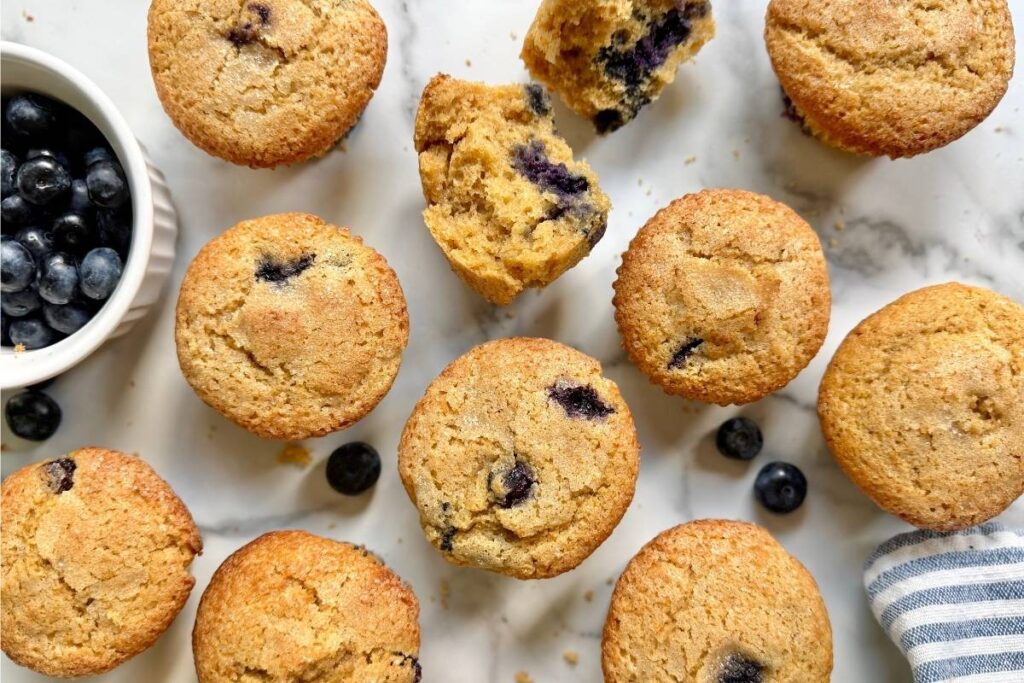 bakery style einkorn blueberry muffins and fresh blueberries on a counter